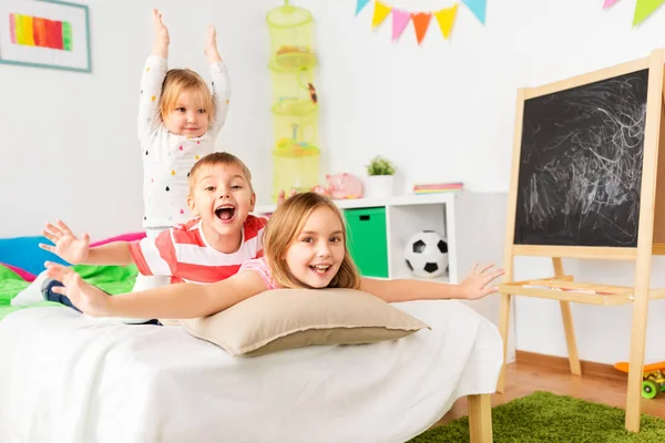 Fröhliche kleine Kinder, die zu Hause Spaß im Bett haben — Stockfoto