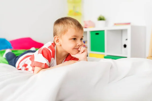 Niño feliz acostado en la cama en casa — Foto de Stock