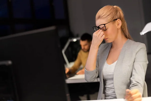 Businesswoman rubbing tired eyes at night office — Stock Photo, Image