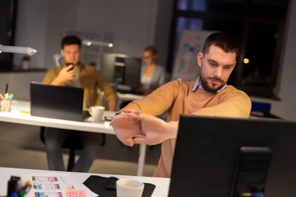 Hombre trabajando hasta tarde en la oficina de noche y estiramiento —  Fotos de Stock