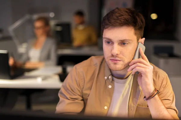 Man calling on smartphone at night office — Stock Photo, Image