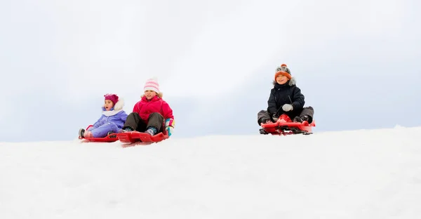 冬天, 孩子们在雪丘下滑雪橇 — 图库照片