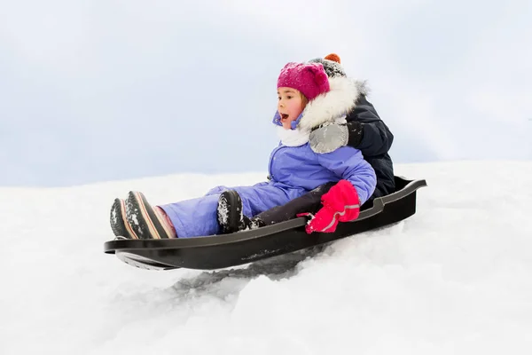 Kleine kinderen glijden op slee bergafwaarts in de winter — Stockfoto