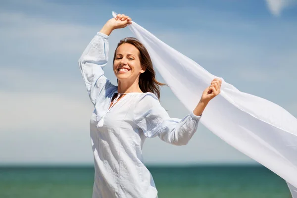 Mujer feliz con chal ondeando en el viento en la playa —  Fotos de Stock