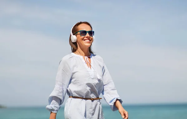 Frau mit Kopfhörern läuft am Sommerstrand entlang — Stockfoto