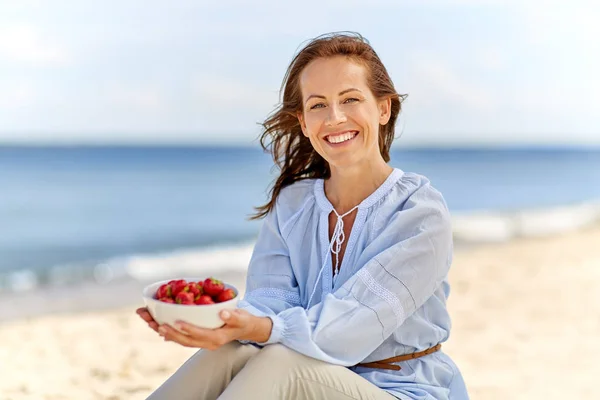 Mujer sosteniendo tazón con fresas en la playa —  Fotos de Stock