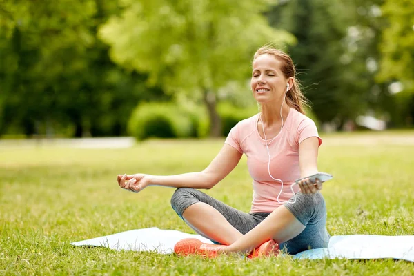 Kvinna med smartphone och vässar mediterar på park — Stockfoto