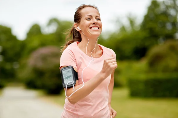 Kobieta ze słuchawkami dodać opaski jogging w parku — Zdjęcie stockowe