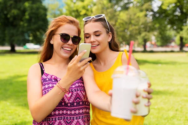 Chicas adolescentes con smartphone y batidos en el parque —  Fotos de Stock