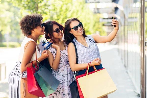 Mulheres com sacos de compras tirando selfie na cidade — Fotografia de Stock