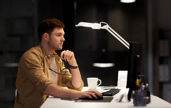 Людина з комп'ютером працює пізно в нічному офісі Стокове Фото