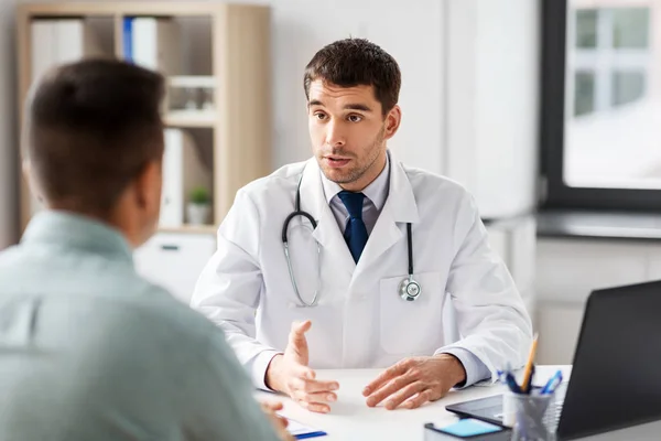 Médico con portátil y paciente masculino en el hospital — Foto de Stock