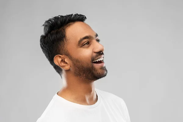 Junger lachender indischer Mann vor grauem Hintergrund — Stockfoto