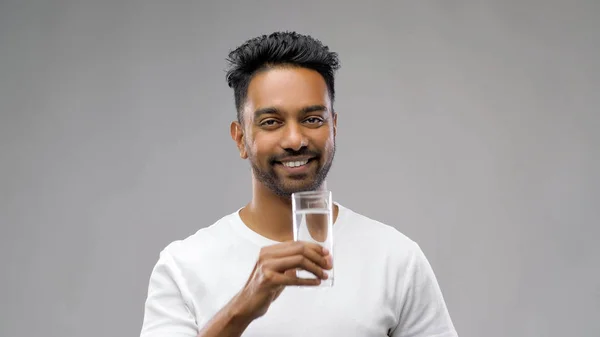 Glücklicher junger indischer Mann trinkt Wasser aus Glas — Stockfoto