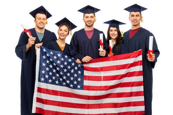Estudiantes graduados con diplomas y bandera americana —  Fotos de Stock