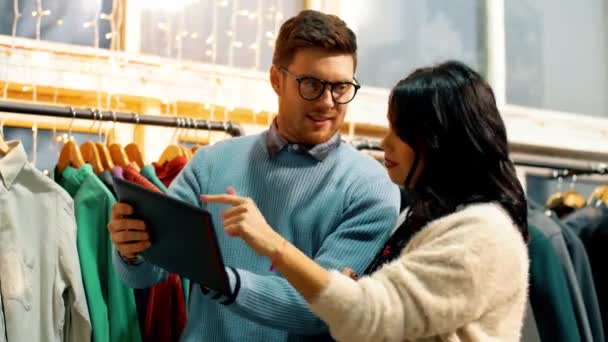 Пара с планшетным компьютером в магазине одежды — стоковое видео