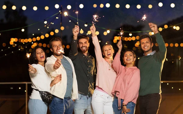 Amigos felices con bengalas en la fiesta en la azotea — Foto de Stock