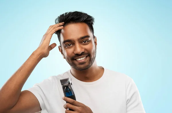 Uomo indiano sorridente con trimmer toccare i capelli — Foto Stock