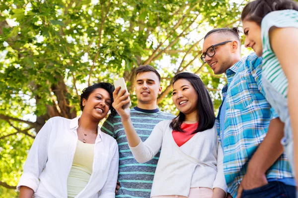 Glückliche Freunde mit Smartphone im Sommerpark — Stockfoto
