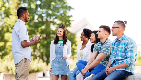 Amigos internacionais felizes falando no parque — Fotografia de Stock