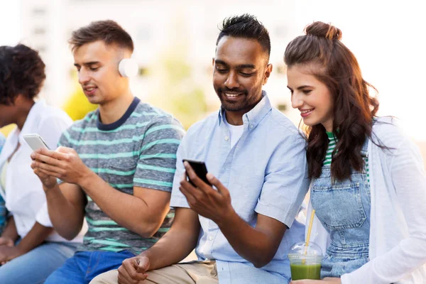 Vrienden met smartphones opknoping in de zomer — Stockfoto