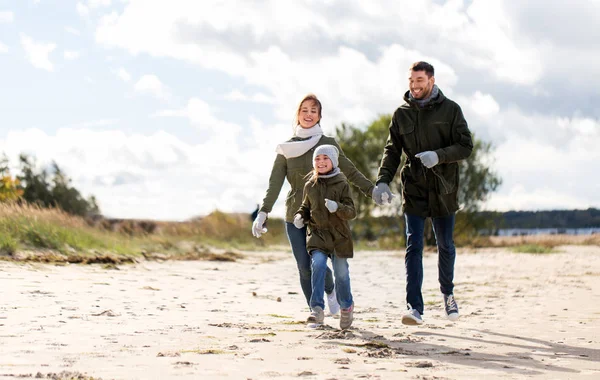 Lycklig familj kör längs hösten beach — Stockfoto