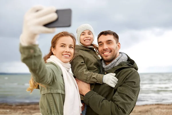 Family taking selfie by smartphone on autumn beach — Stock Photo, Image