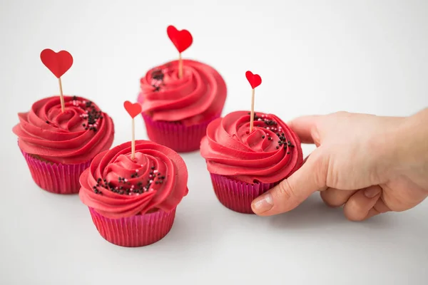 Primer plano de la mano tomando cupcakes con palitos de corazón — Foto de Stock