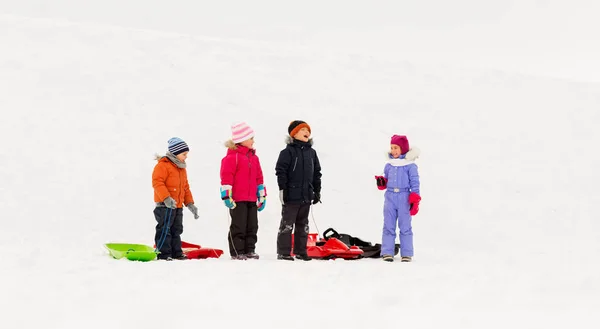 Gelukkig weinig kinderen met sleeën in de winter — Stockfoto