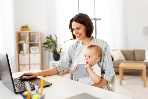 Werkende moeder met baby jongen en laptop thuis — Stockfoto