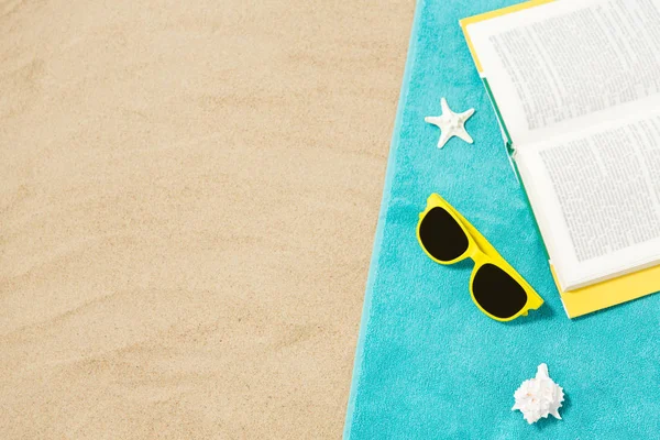 Solglasögon och bok på strandhandduk på sand — Stockfoto