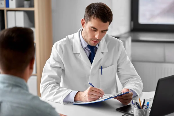 Médecin avec presse-papiers et patient masculin à l'hôpital — Photo