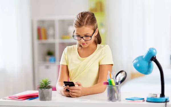 Estudiante chica con smartphone haciendo la tarea — Foto de Stock