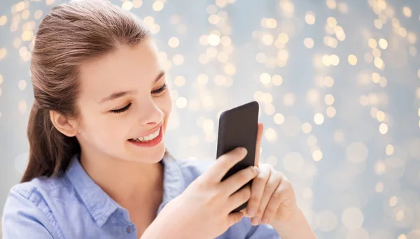 Mensajería de chica en el teléfono inteligente a través de luces festivas —  Fotos de Stock