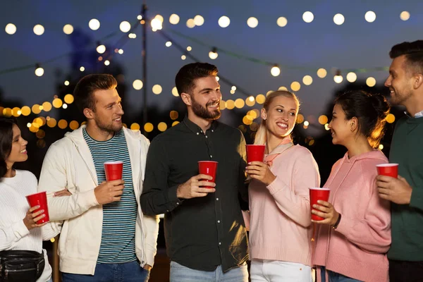 Amigos con copas de fiesta en la azotea por la noche —  Fotos de Stock