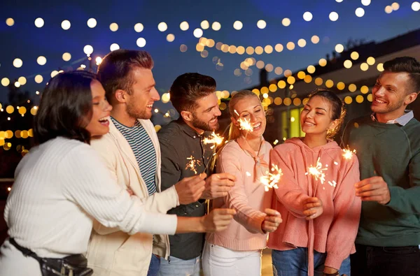 Amigos felizes com sparklers na festa no telhado — Fotografia de Stock