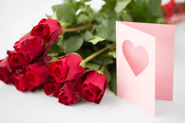 Close up de rosas vermelhas e cartão de saudação com coração — Fotografia de Stock