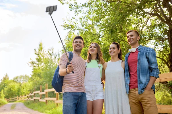 Friends take picture by smartphone on selfie stick — Stock Photo, Image