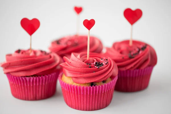 Perto de cupcakes com paus de coquetel de coração Imagens De Bancos De Imagens