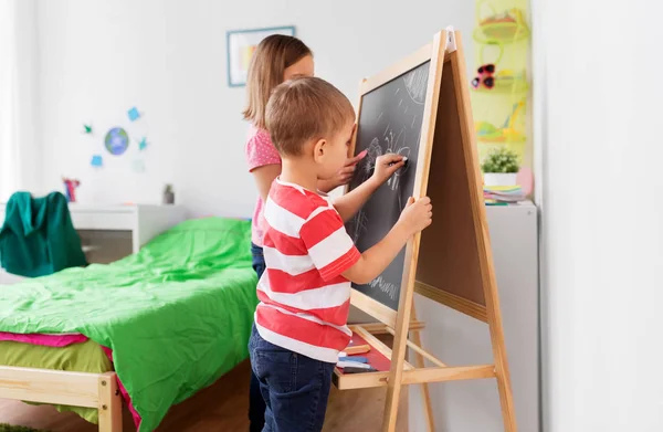 Happy kids drawing on chalk board at home — Stock Photo, Image