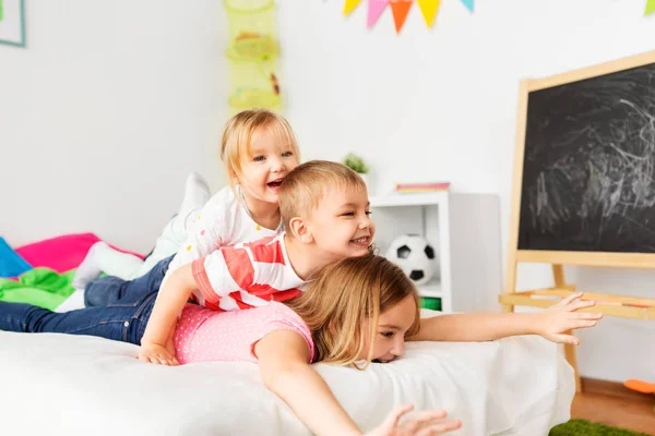 Счастливые маленькие дети, веселящиеся в постели дома — стоковое фото