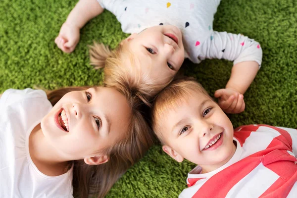 Счастливые маленькие дети, лежащие на полу или ковре — стоковое фото