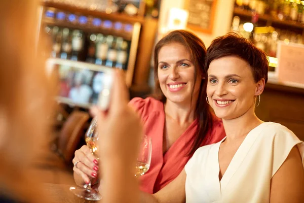 Frau fotografiert Freunde mit Smartphone an Weinbar — Stockfoto