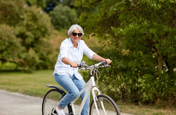 Gelukkig senior vrouw fietsten in zomer park — Stockfoto