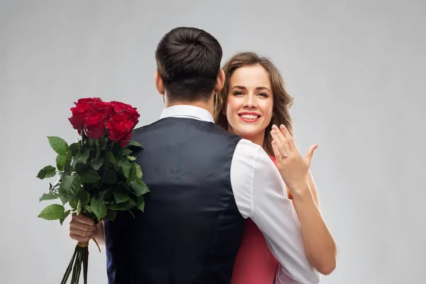 Mulher com anel de noivado e rosas abraçando o homem — Fotografia de Stock
