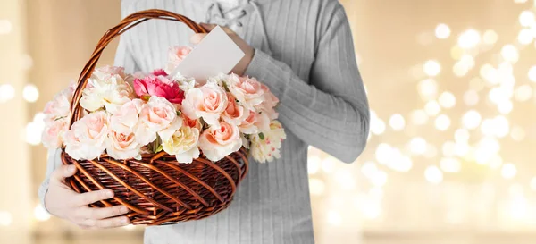 Man holding basket of flowers with note — Stock Photo, Image