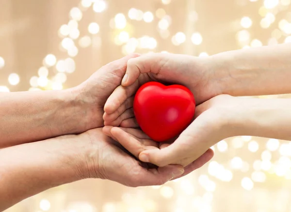 Anziano e giovane uomo mani tenendo il cuore rosso — Foto Stock