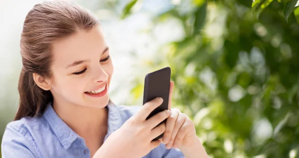 Chica feliz con teléfono inteligente sobre fondo natural — Foto de Stock
