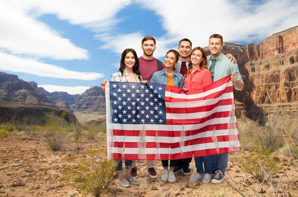 Amigos com bandeira americana sobre grande canyon — Fotografia de Stock
