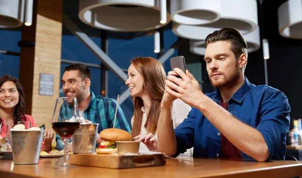 Messagerie homme sur smartphone au restaurant — Photo